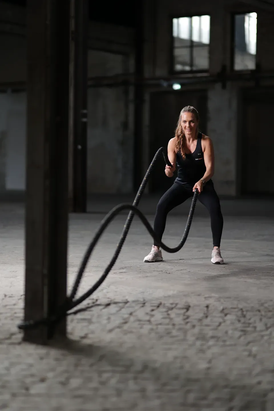 Frau trainiert mit Battle Ropes in einer Industriehalle